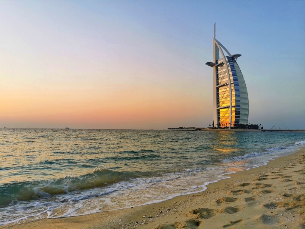 Dubai A stunning sunset view of Burj Al Arab from Jumeirah Beach, Dubai with gentle waves and golden sands.