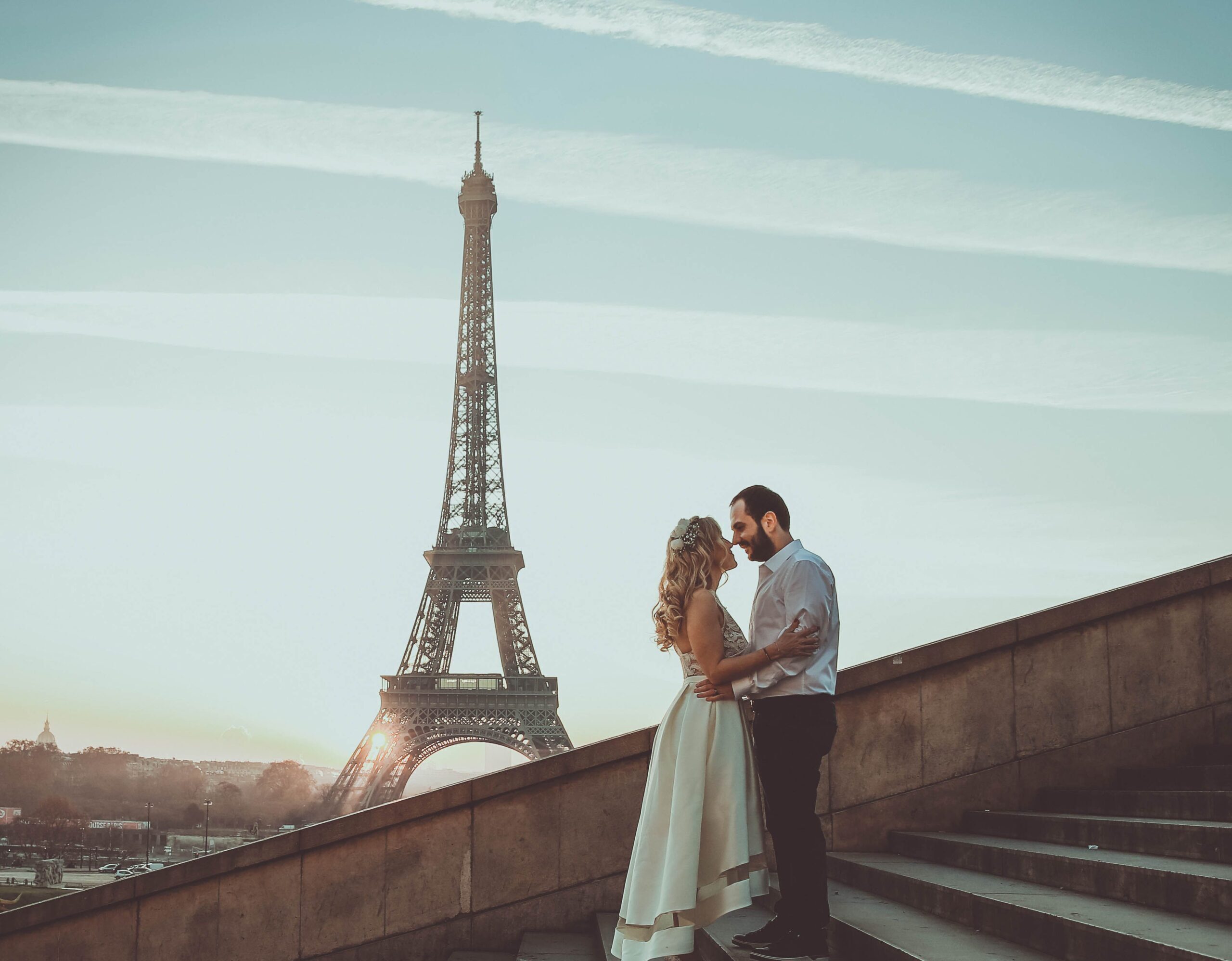 A romantic embrace of a couple at sunset with the Eiffel Tower in the background.