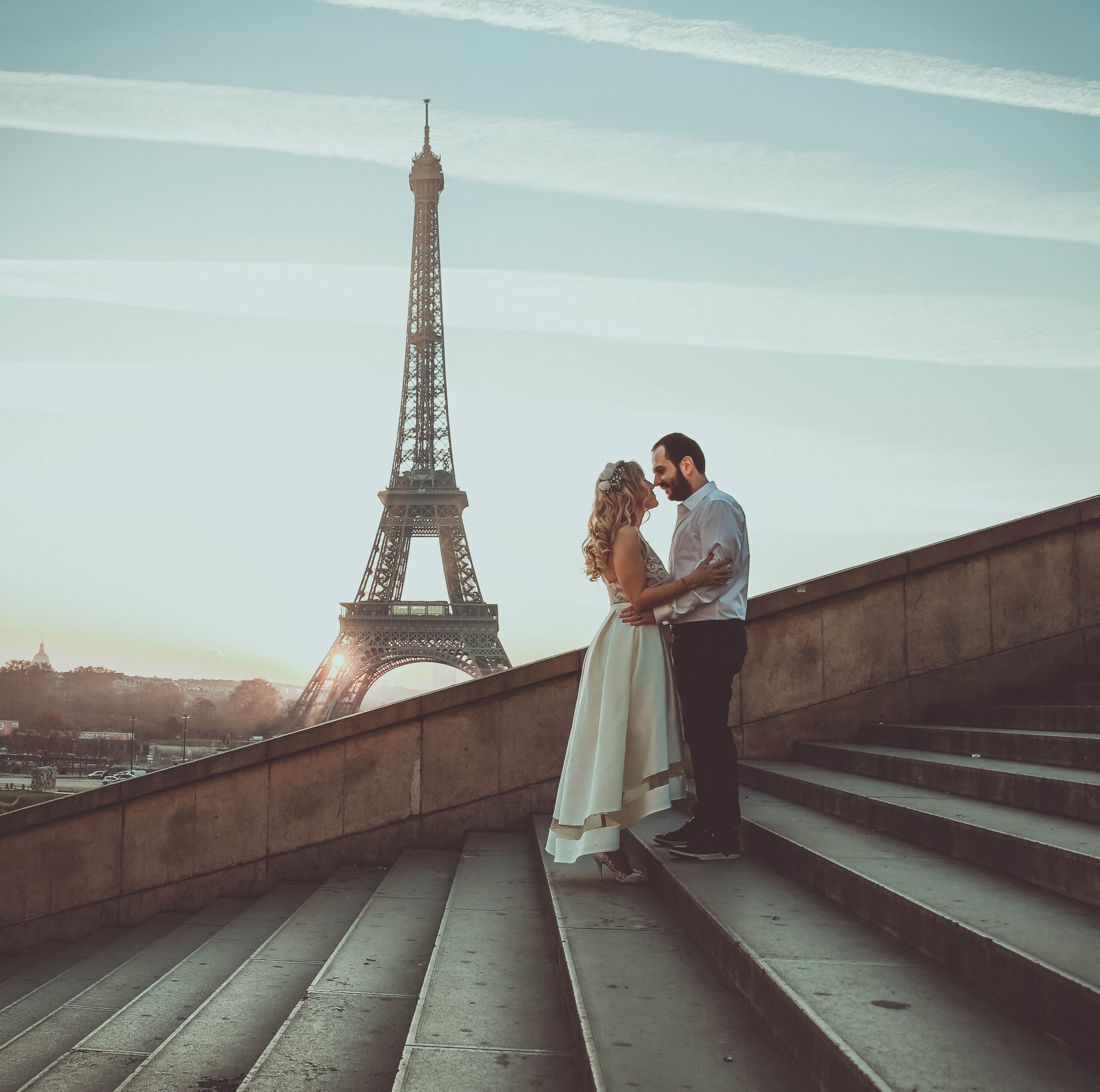 A romantic embrace of a couple at sunset with the Eiffel Tower in the background.