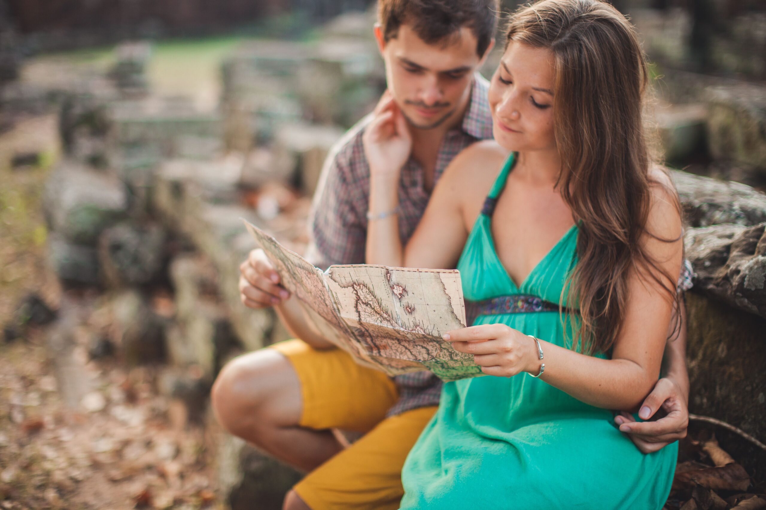A young couple enjoys a romantic moment while reading a map in an ancient ruins setting.
