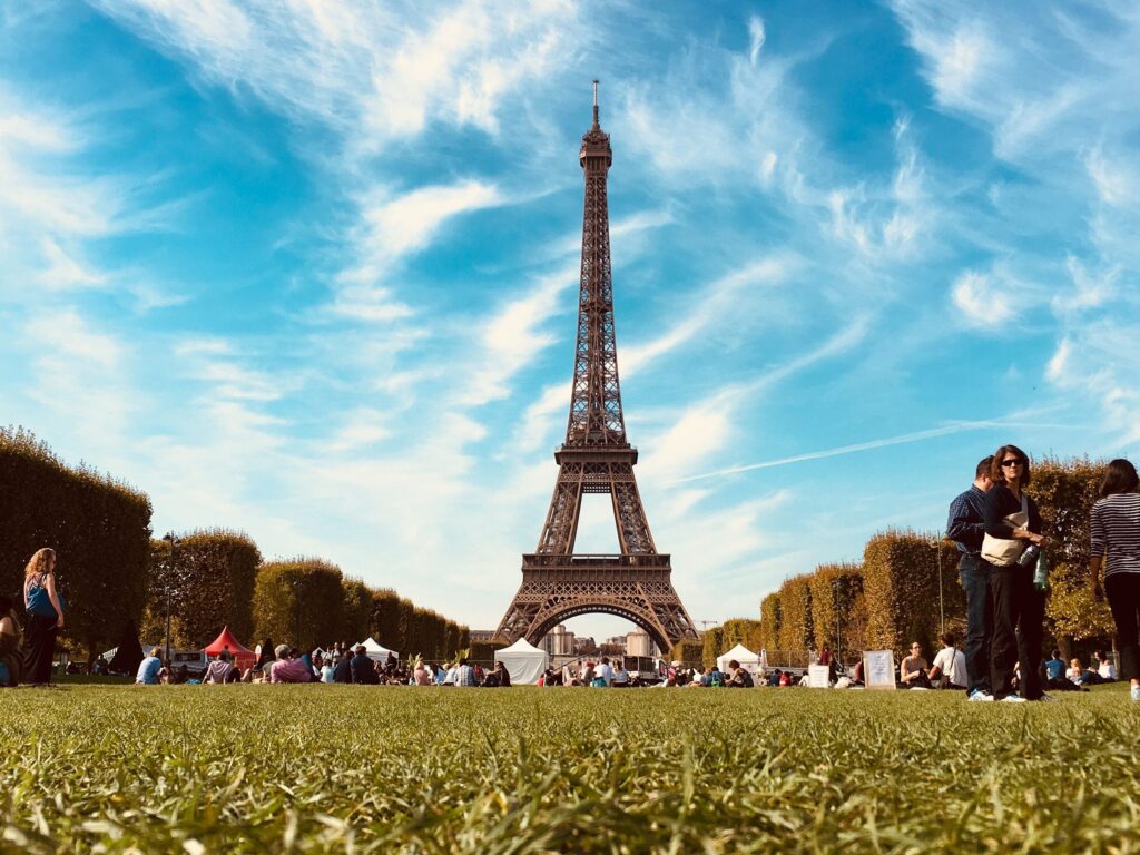 A sunny day in Paris with people relaxing in a park near the Eiffel Tower, showcasing urban leisure.