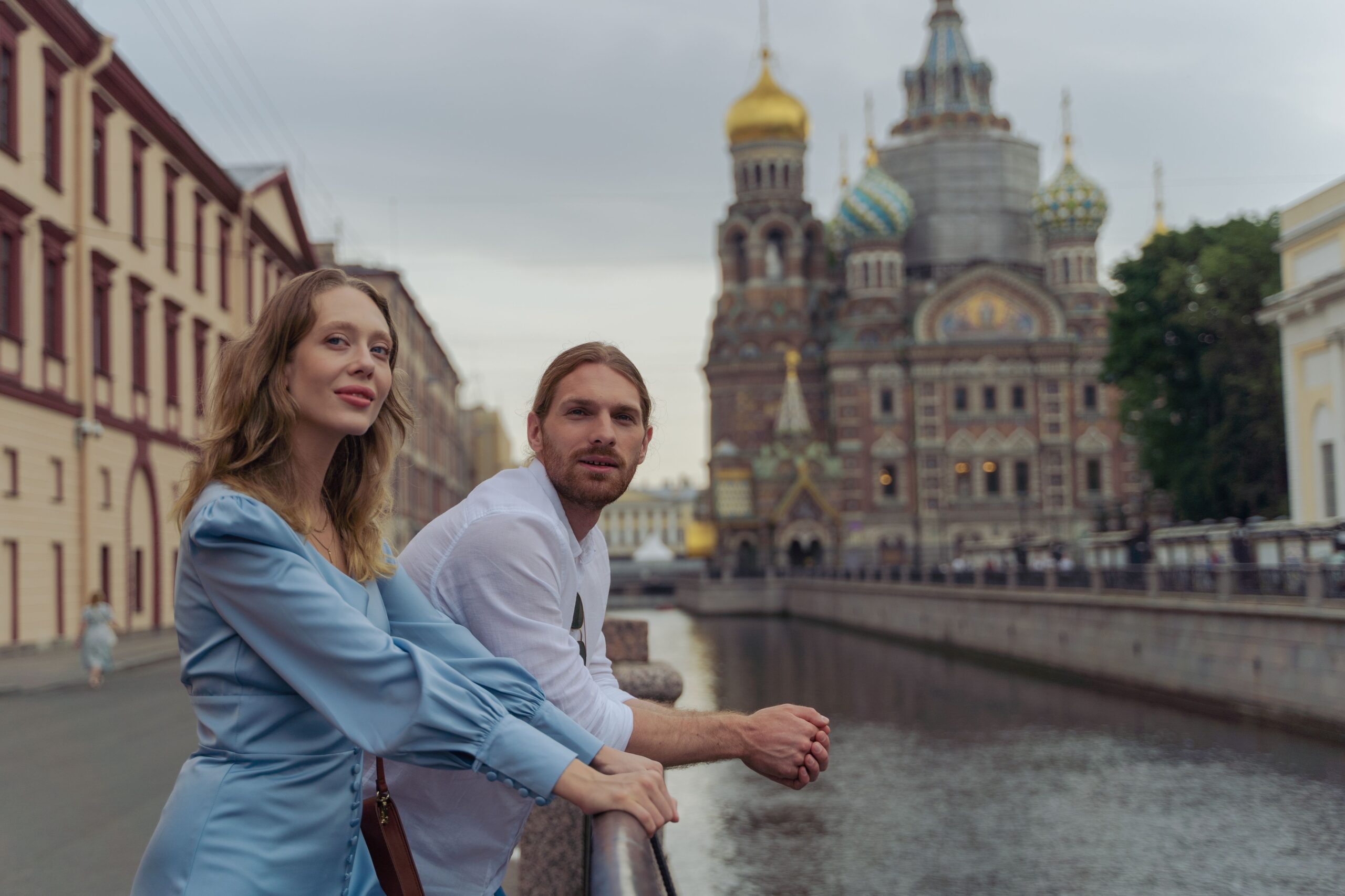 A couple enjoys a scenic view on a bridge near the Church of the Savior on Blood in Saint Petersburg.